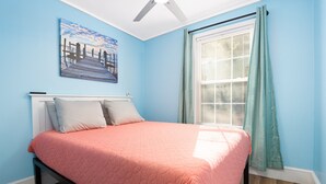A bedroom with a bed, a ceiling fan, a window with curtains, and a painting on the wall. - Serene & Quiet Cottage | Office | 5 Min to RH (Rock Hill)