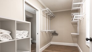 Ein begehbarer Kleiderschrank mit offenen Regalen, einer Kleiderstange und Holzboden.