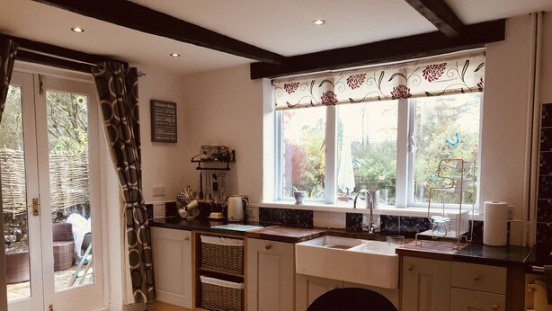 A kitchen with a wooden table, white cabinets, and a window with a view of greenery. - 3 Bedroom Country Retreat - Dogs Welcome (Appleby-in-Westmorland)