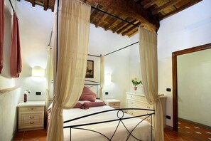 A bedroom with a four-poster bed, two bedside tables, a nightstand, a mirror, and a door. - Aleri - Just a Few Meters from the Train Station and the Historic Center (Firenze)