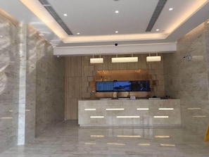 A reception area with a marble floor, a reception desk, and a flat-screen TV mounted on the wall. - Greentree Inn Yancheng Jiefang Road Express Hotel (Yancheng)