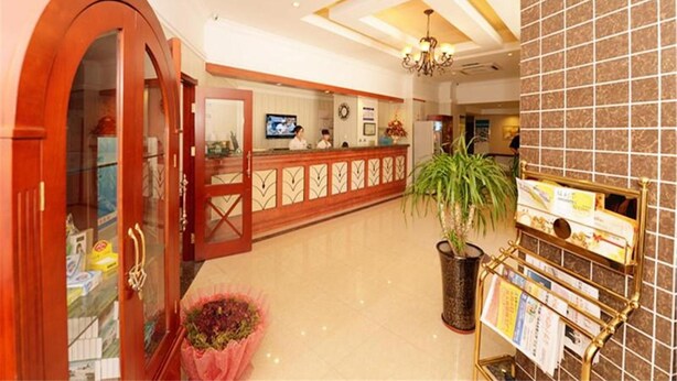 A hotel lobby with a reception desk, a large potted plant, and a bulletin board. - Greentree Inn Qinhuangdao Olympic Center Express (Qinhuangdao)