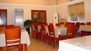 A dining area with multiple tables and chairs, a potted plant, and a sign reading "AUOMA". - Greentree Inn Qinhuangdao Olympic Center Express (Qinhuangdao)