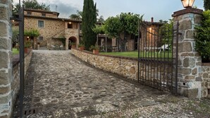 A stone pathway leading to a rustic stone building with a gated entrance and a lantern post.