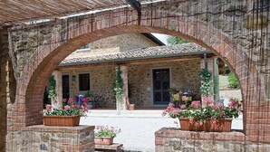 A stone building with a tiled roof, an arched entrance, and potted plants.