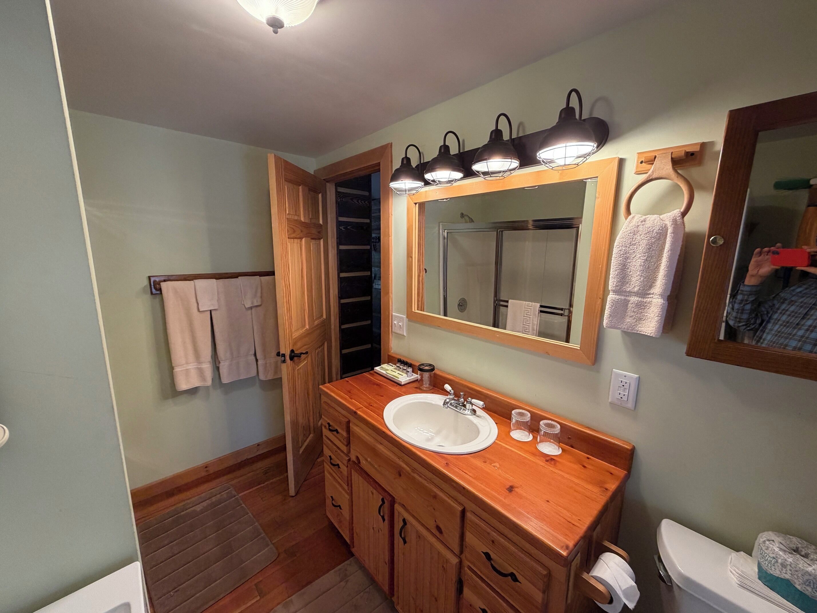 A bathroom with a wooden vanity, a large mirror, and a shower area.