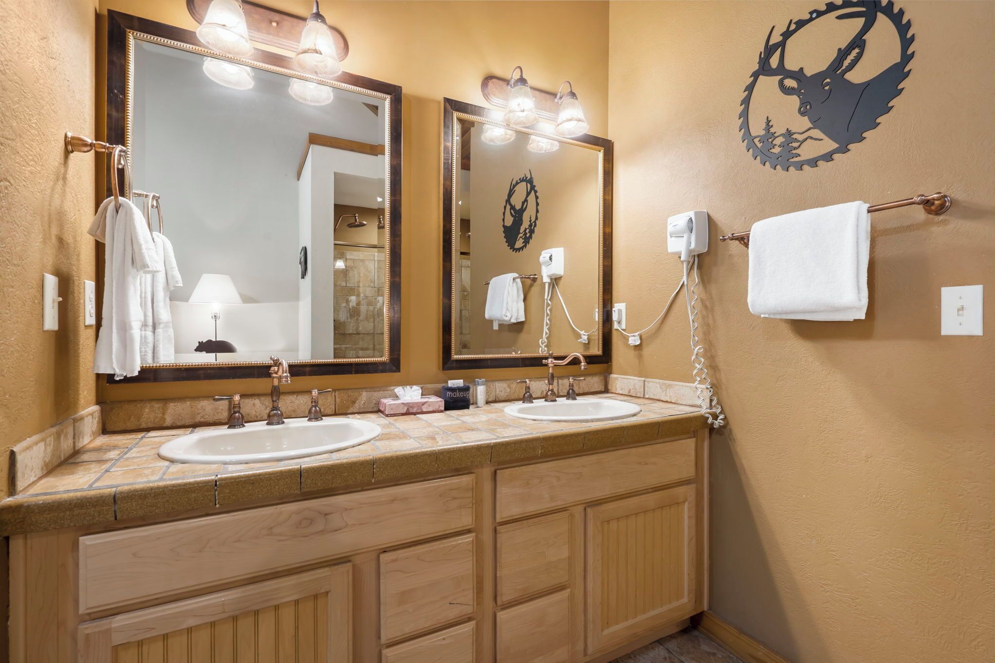 A bathroom with two sinks, a large mirror, and a towel rack.