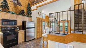 A kitchen with a stove, microwave, refrigerator, and wooden cabinets.