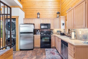 A compact kitchen with wooden cabinets, a stainless steel refrigerator, a microwave, an oven, and a dishwasher.
