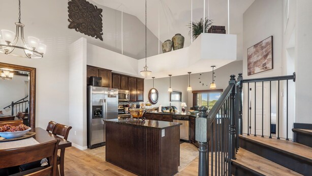 Una cocina amplia con una isla central, piso de madera y electrodomésticos modernos.