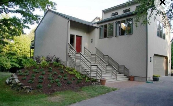 Une maison moderne à deux étages, avec une porte rouge, un escalier et un garage.