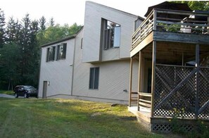 Une maison moderne à deux étages, dotée d’un balcon et d’une voiture garée dans l’allée.