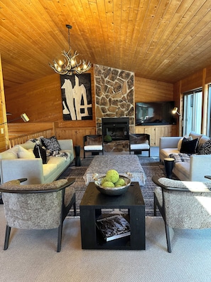 A cozy living room with a fireplace, wooden ceiling, and a stone accent wall.