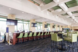 A bar area with multiple seating options, including bar stools and high chairs, and a television mounted on the wall.