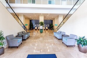 A lobby with a central seating area, a staircase, and a sign reading 'EMERALD BEACH'.