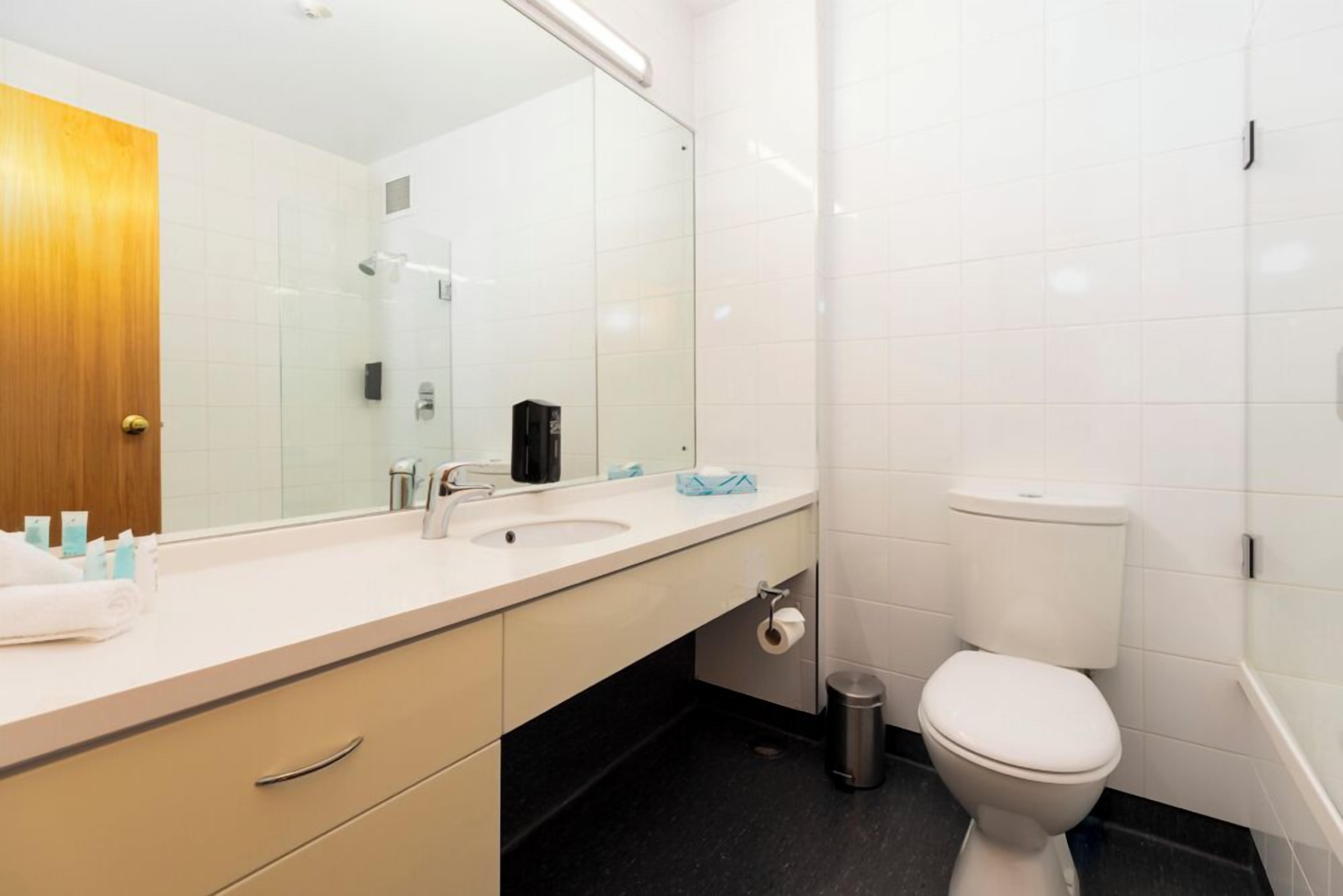Une salle de bain moderne avec un lavabo blanc, un miroir et des toilettes.