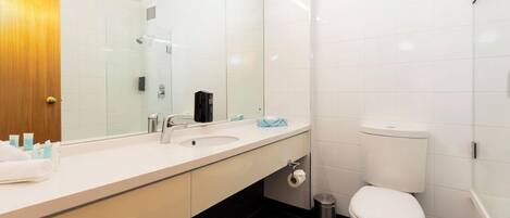A modern bathroom with a white sink, mirror, and toilet.