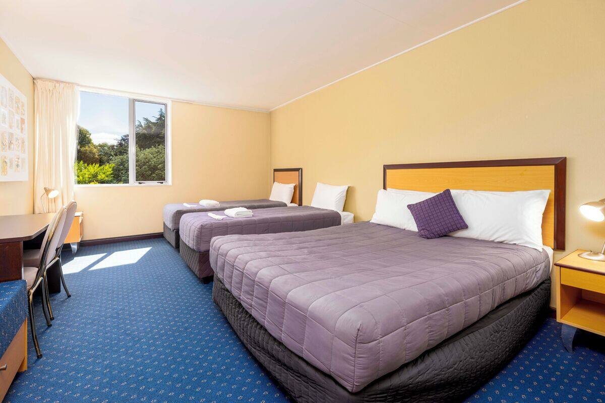 A hotel room with two beds, a desk, and a chair.
