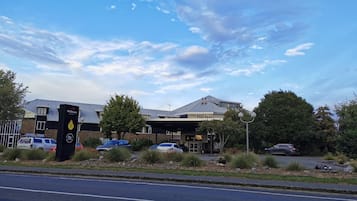 Un edificio dal design moderno, con tetto piatto e ampie finestre. Un'area di parcheggio con diverse auto parcheggiate davanti.