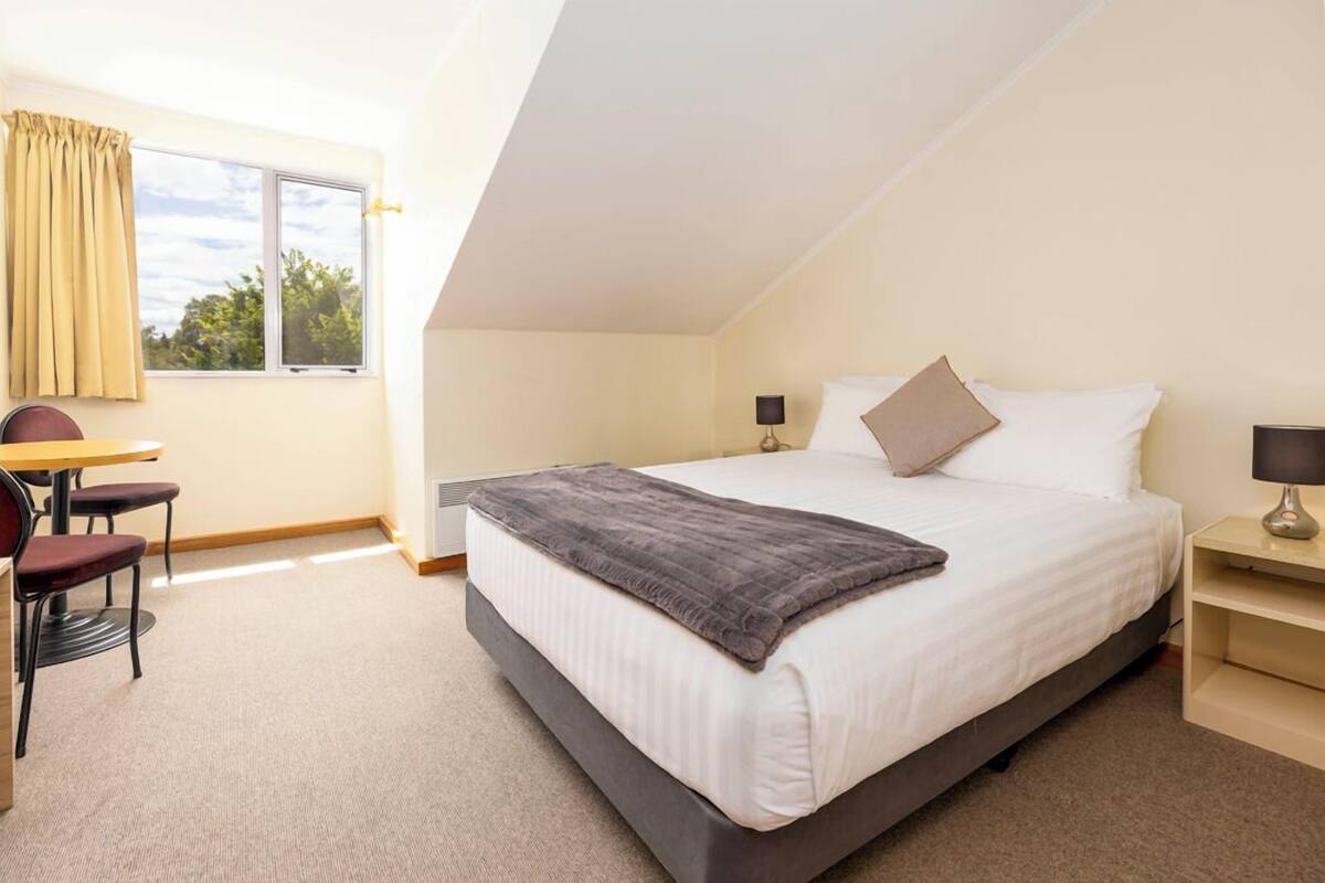 A bedroom with a bed, a desk, and a chair.