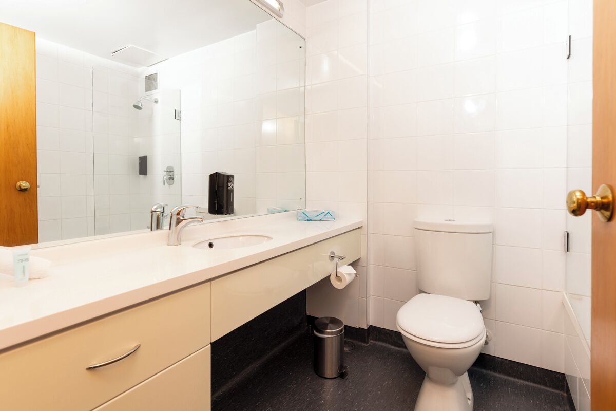 Een moderne badkamer met een wit wastafelmeubel, spiegel en toilet.