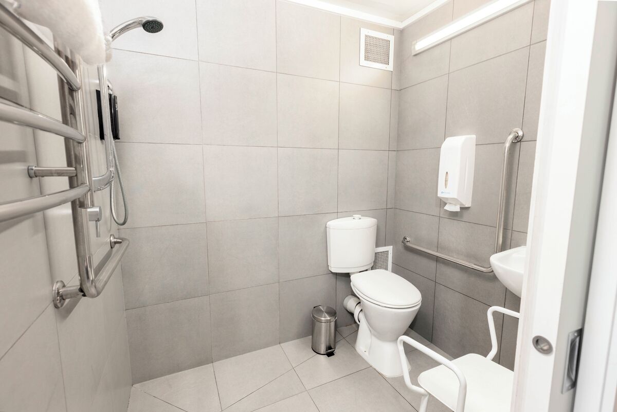 A modern bathroom with a toilet, bidet, and hand dryer.