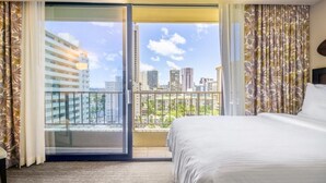 A hotel room with a bed, a view of the city through a balcony, and a sliding glass door. - Waikiki | Tropical Escape | Pool & Saun (Honolulu)