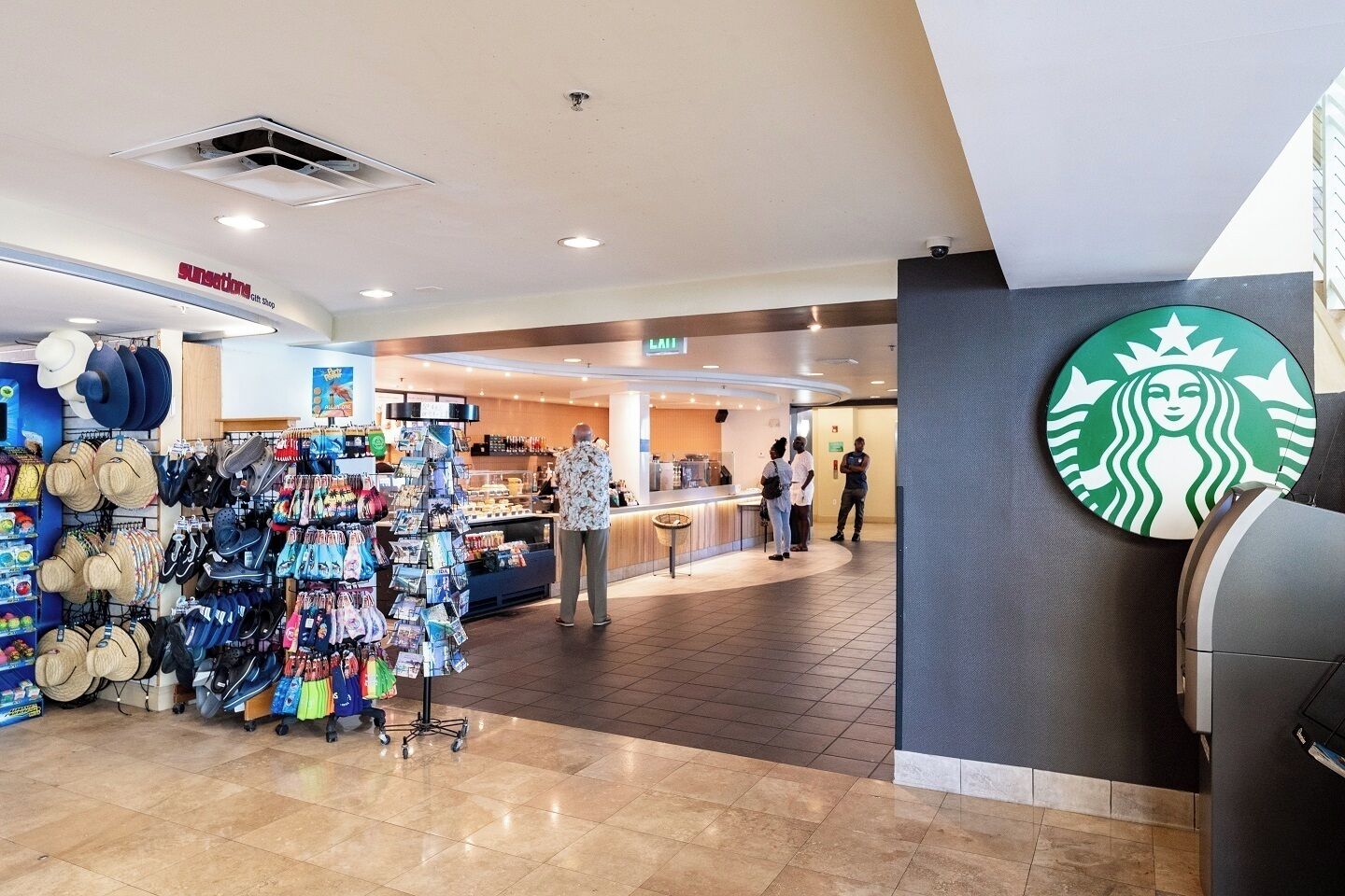 A shopping area with a kiosk, a Starbucks logo, and a ceiling vent.