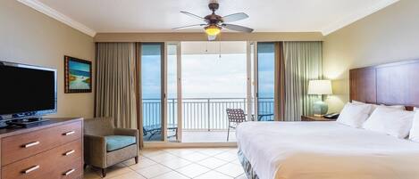 Ein Hotelzimmer mit Bett, Fernseher, Schreibtisch, Stuhl und einem Balkon mit Aussicht.