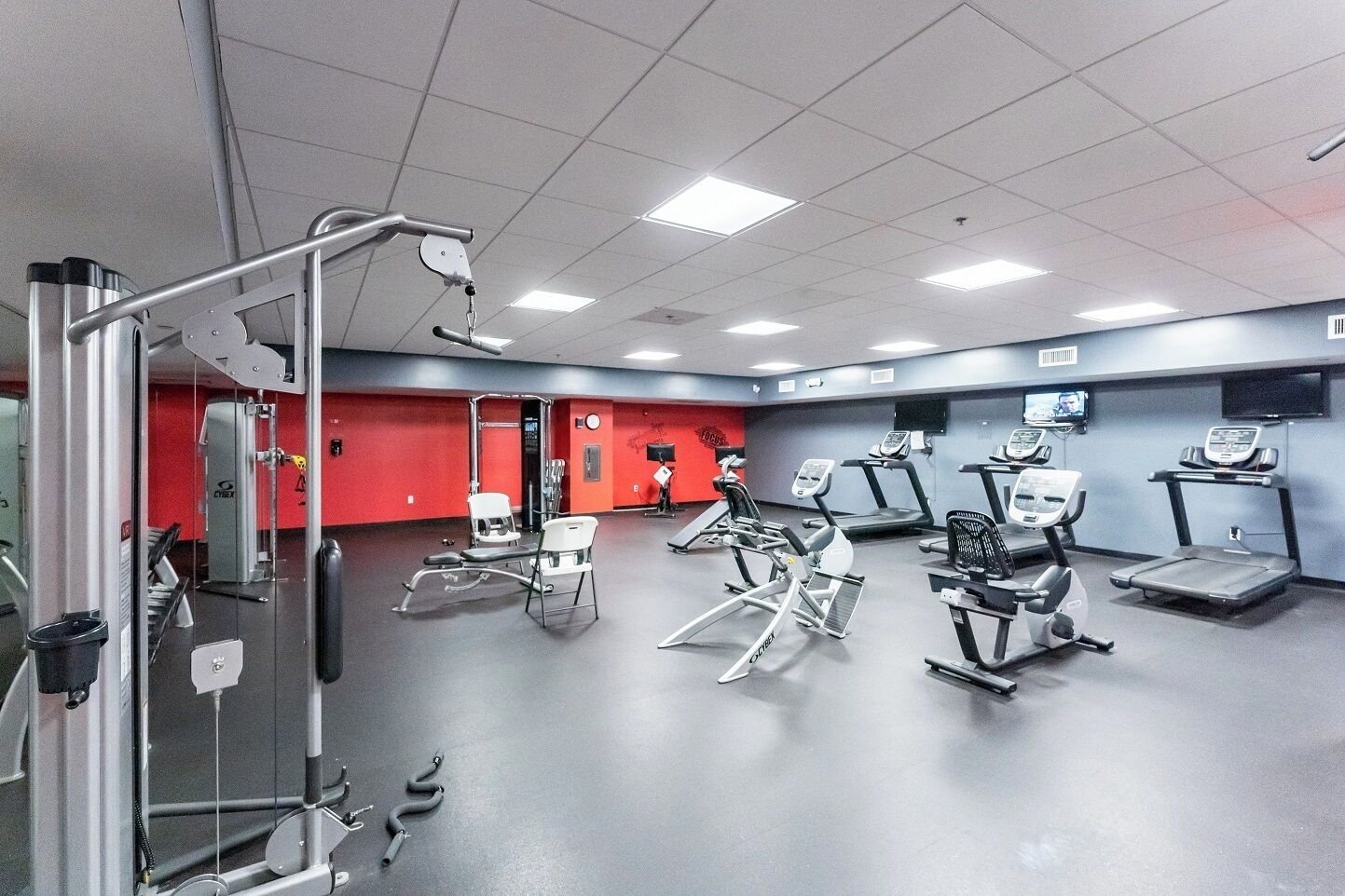 Ein Fitnessstudio mit verschiedenen Trainingsgeräten, darunter Laufbänder und Kraftgeräte.