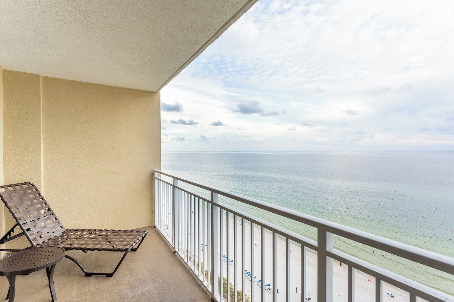 A balcony with a view of the ocean, a chair, and a railing.