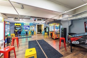 Um salão de jogos indoor com diversas máquinas de jogos, banquetas e uma mesa temática de Star Wars.