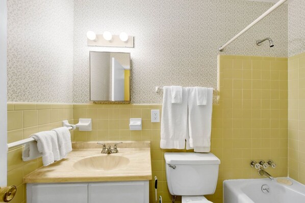 Un baño con lavamanos, espejo, inodoro y bañera.