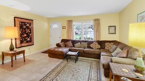 A living room with a brown sofa set, a patterned rug, and a lamp. - Carole Cottage - close to golf, tennis, and the beach (Jekyll Island)