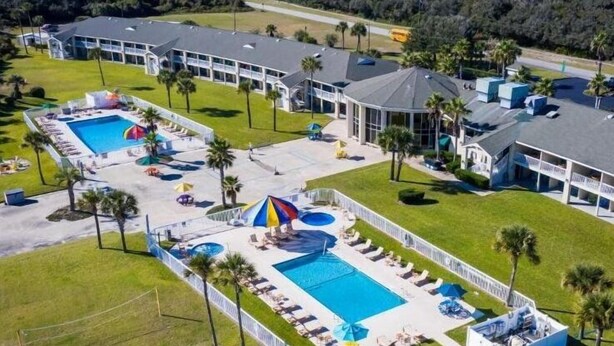 An aerial view of a resort with multiple swimming pools, sun loungers, and a large building with a curved roof. - Carole Cottage - close to golf, tennis, and the beach (Jekyll Island)