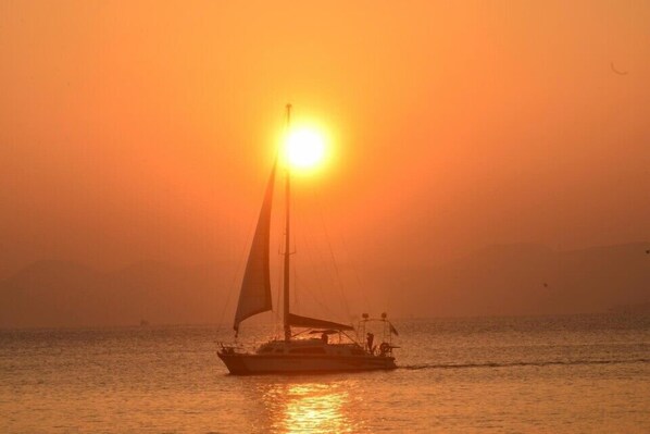 Un voilier sur des eaux calmes, au coucher du soleil.