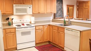 A kitchen with wooden cabinets, a microwave, stove, sink, and dishwasher. - Boyne Mountain, Disciples Village Condo - Steps To Boyneland Run (Boyne falls)