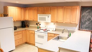 A kitchen with wooden cabinets, a white refrigerator, a microwave, a stove, and a sink. - Boyne Mountain, Disciples Village Condo - Steps To Boyneland Run (Boyne falls)