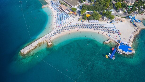 An aerial view of a coastal area with a beach, a marina, and a hotel. - Villa Carpe Diem (Selce)