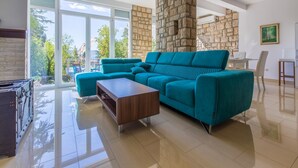 A modern living room with a teal sofa, a wooden coffee table, and a stone accent wall. - Villa Carpe Diem (Selce)