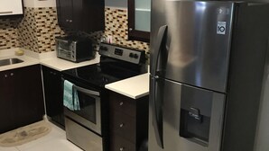 A compact kitchen with a stainless steel refrigerator, a built-in oven, a toaster, and a microwave. - MODERN LUXURY 1BR/1BA/COZY/VIEWS OF KINGSTON (Kingston)