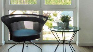 A modern room with a large window, a black mesh chair, and a small round table with a potted plant. - Landliebe by Interhome (Attendorn)