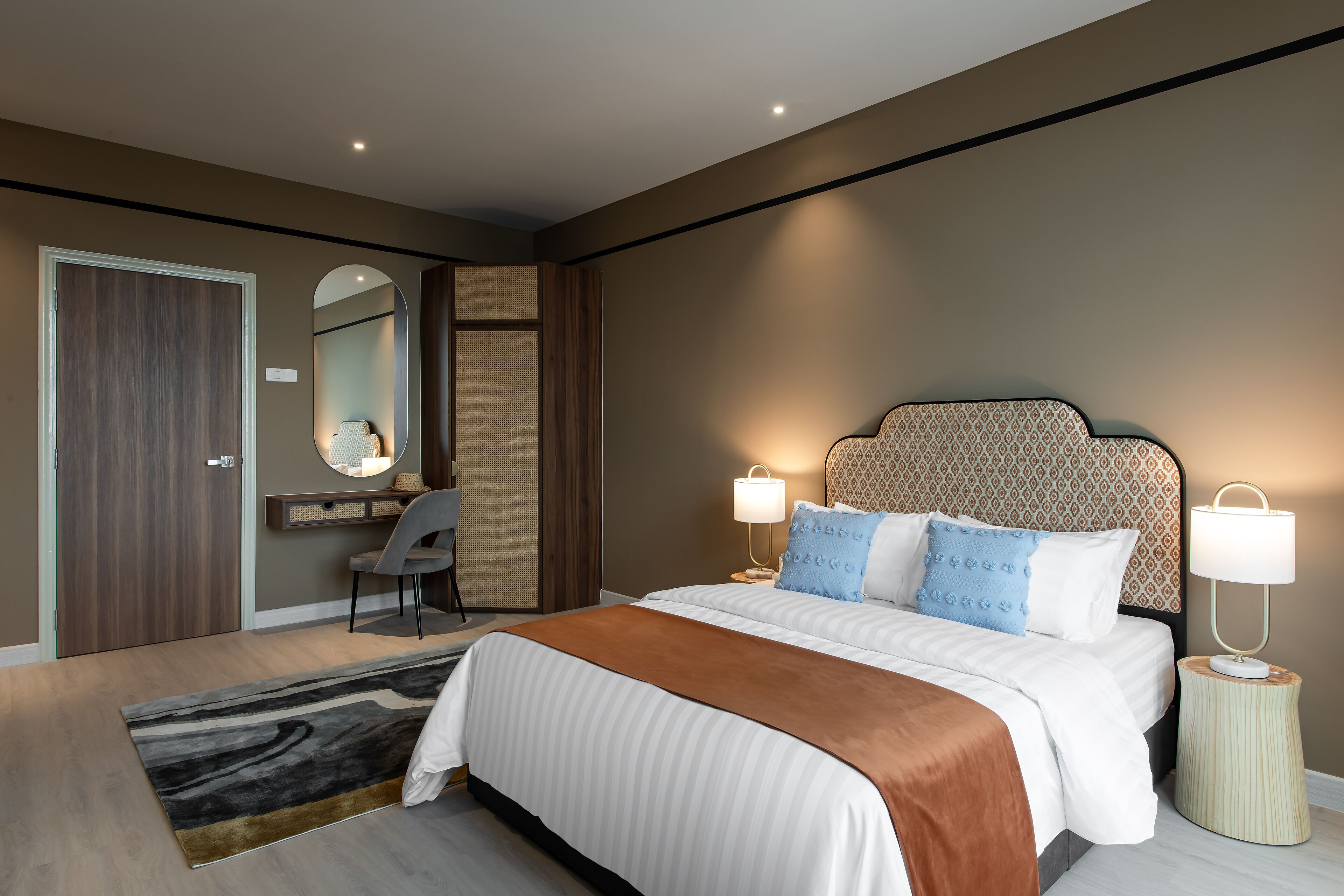 Ein modernes Hotelzimmer mit einem großen Bett, zwei Nachttischen mit Lampen, einem Schreibtisch mit Stuhl und einem großen Spiegel.