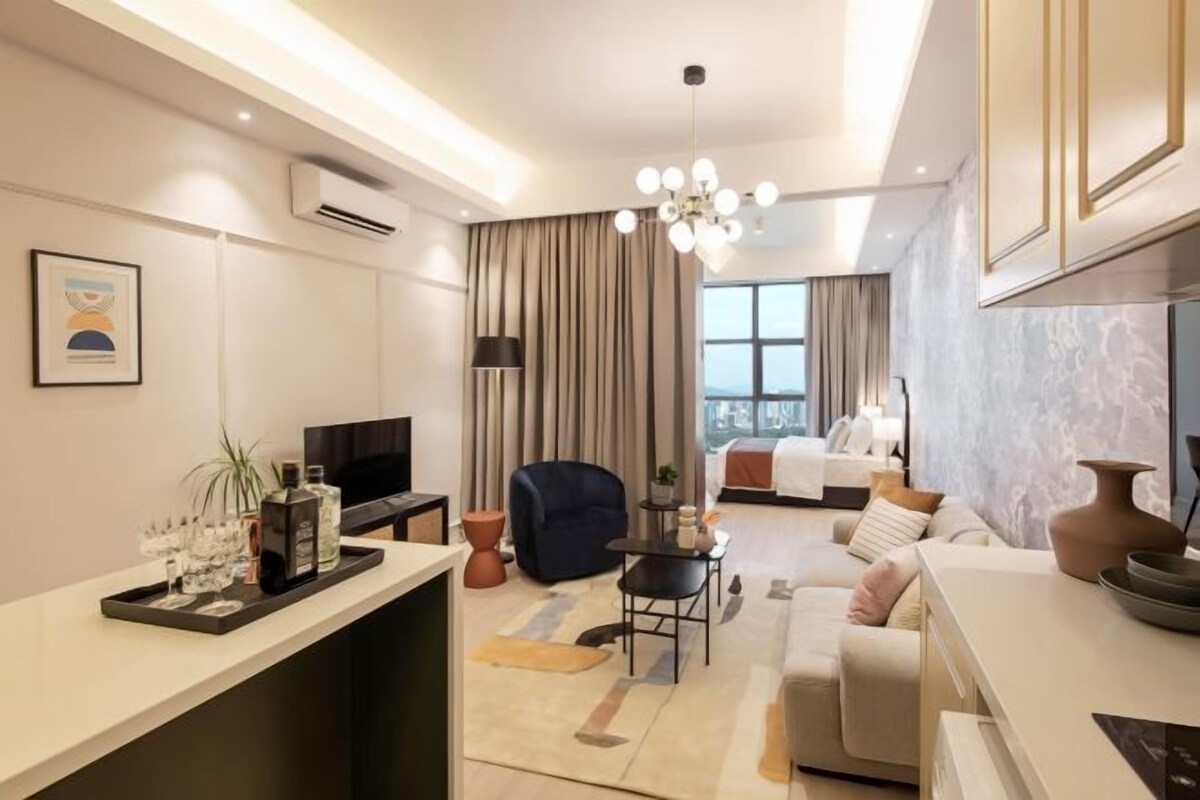 Una habitación de hotel moderna con sala de estar, un sofá, un televisor, una mesa de comedor y un amplio ventanal.