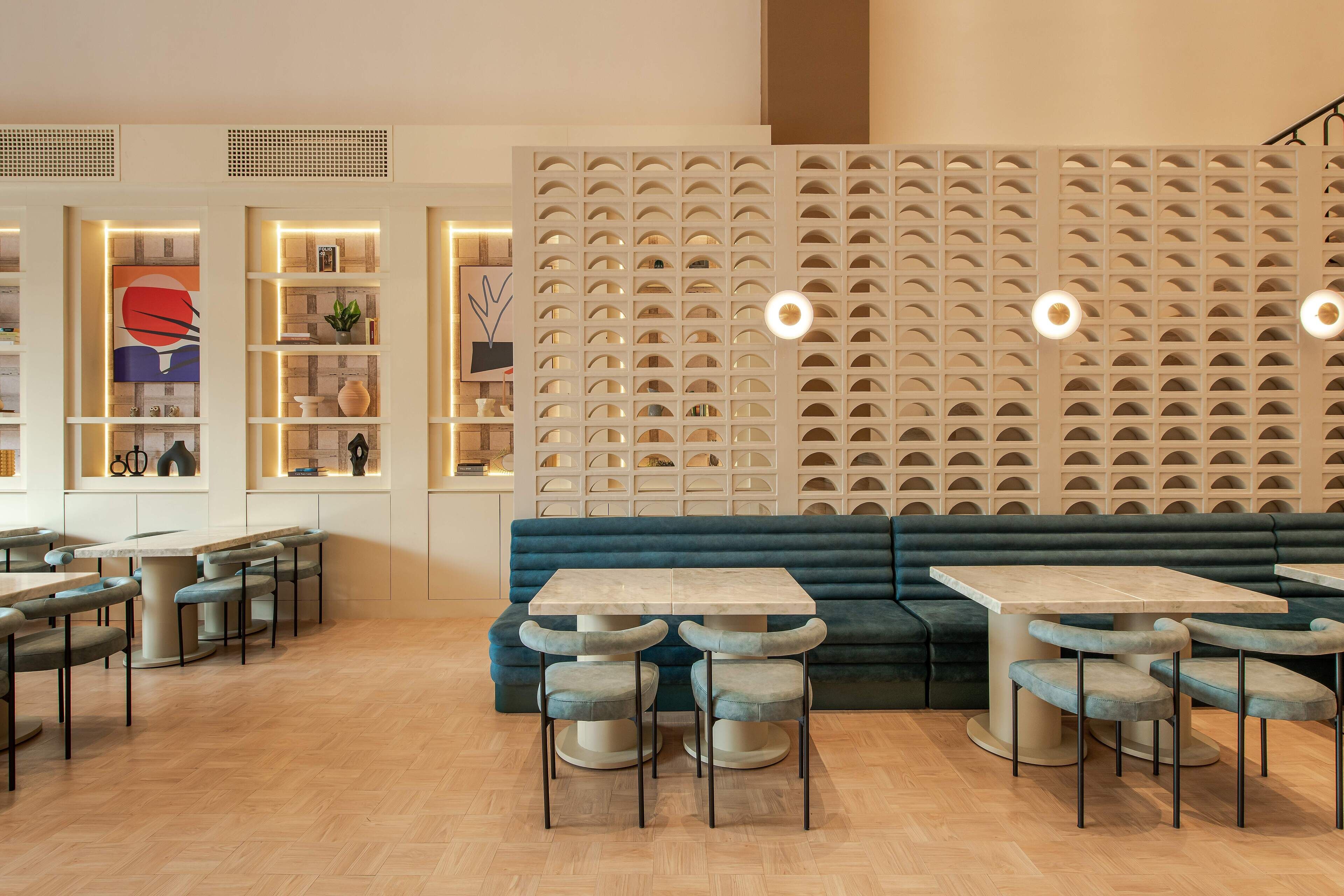 Un interior moderno con un sofá azul, mesas y sillas de madera.
