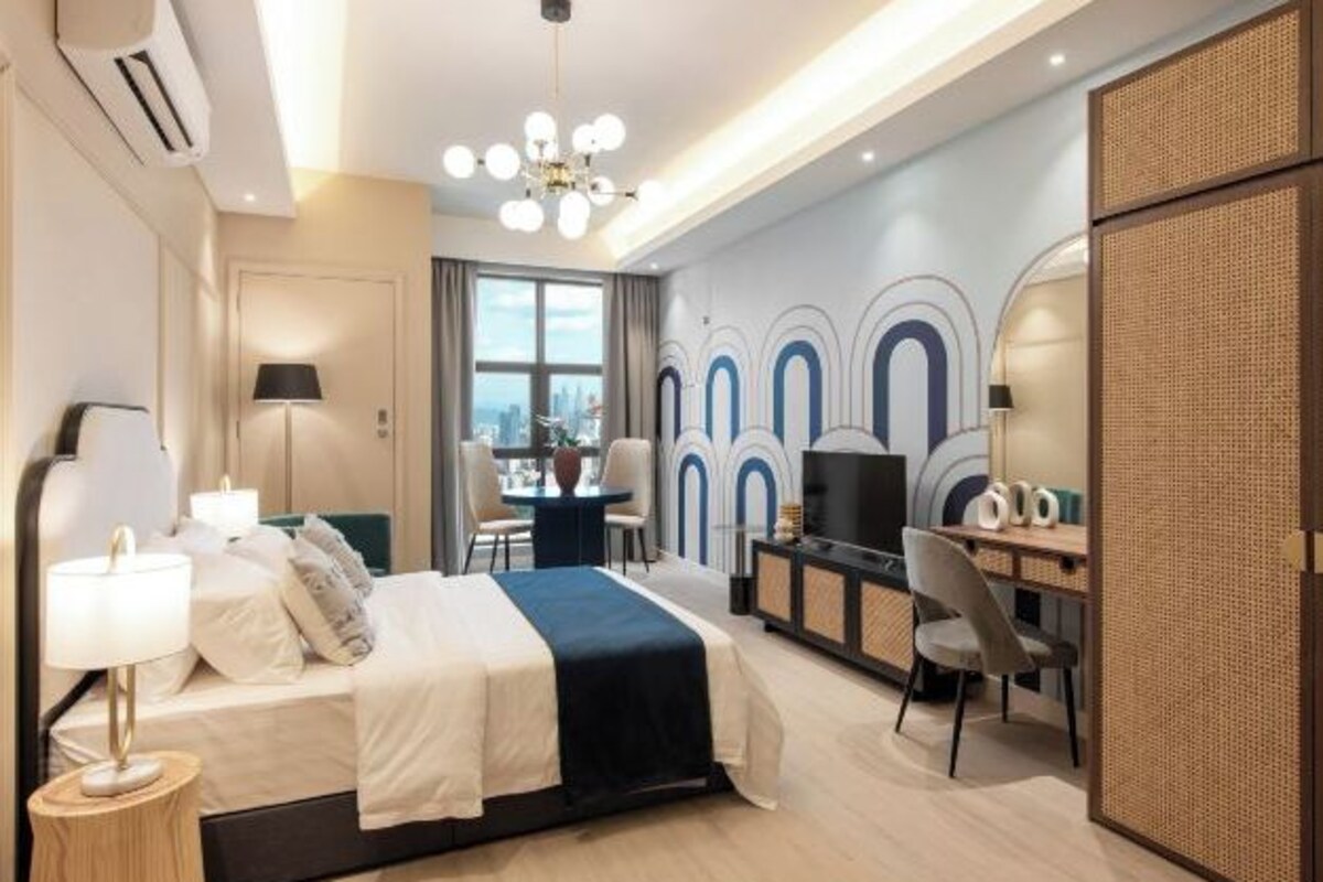 Una habitación de hotel moderna con cama, escritorio, televisor y vista a la ciudad.