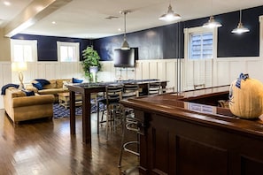 A modern kitchen with dark walls, wooden bar stools, and pendant lighting. - Prime Location! Modern Comfort 1 Block to Gate 1 w/ Parking & Walkability (Annapolis)