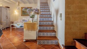 A staircase with patterned tiles, a white cabinet, and a vase with flowers.
