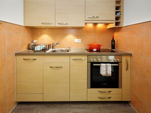Eine kleine Küche mit Holzausstattung, einem eingebauten Backofen und einem Spülbecken.