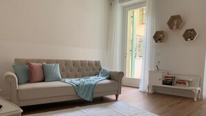 Un salon avec un canapé beige, un tapis à motifs et un banc blanc sur lequel sont posés des livres.